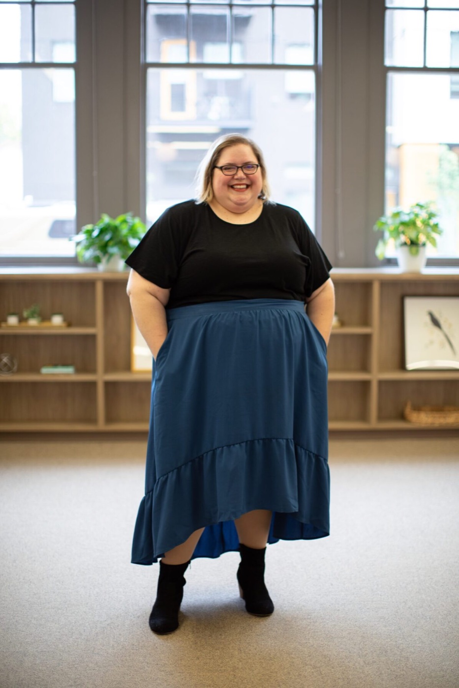 Smiling person standing in a warm, plant-filled office