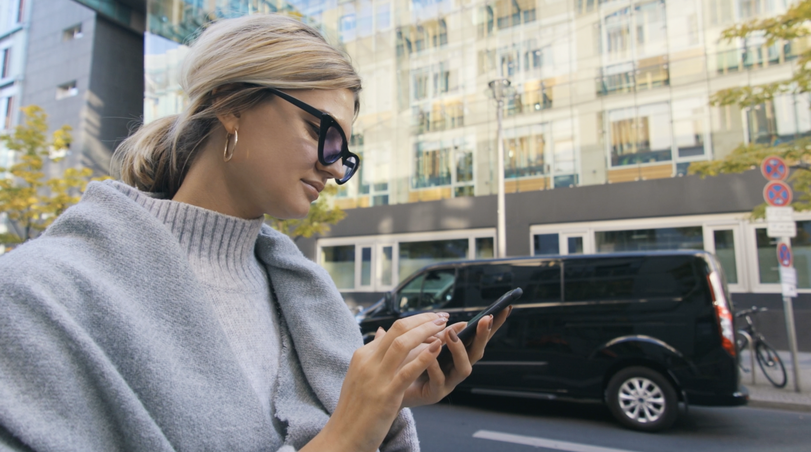 CAELIS creator checking phone in city setting.