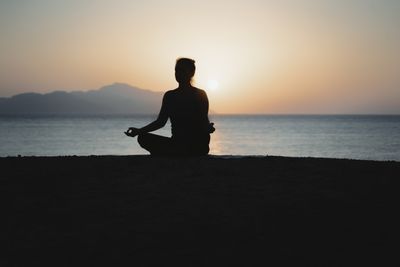 Silhouette meditating by the sea