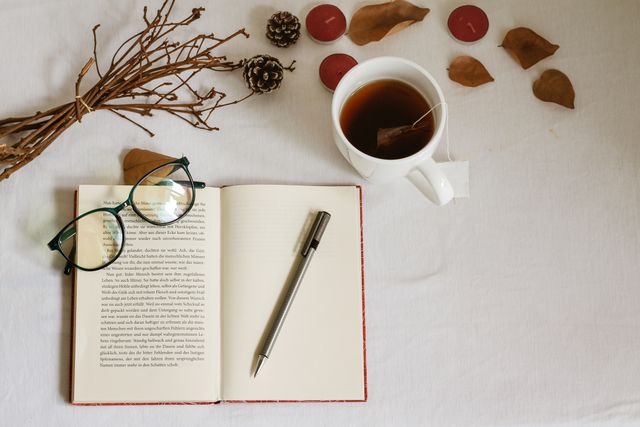 Open journal with a handwritten note beside a plant and cup of tea