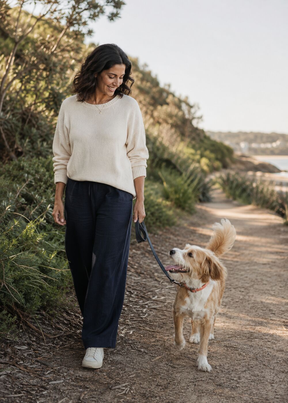 A woman walking with her dog on a coastal path