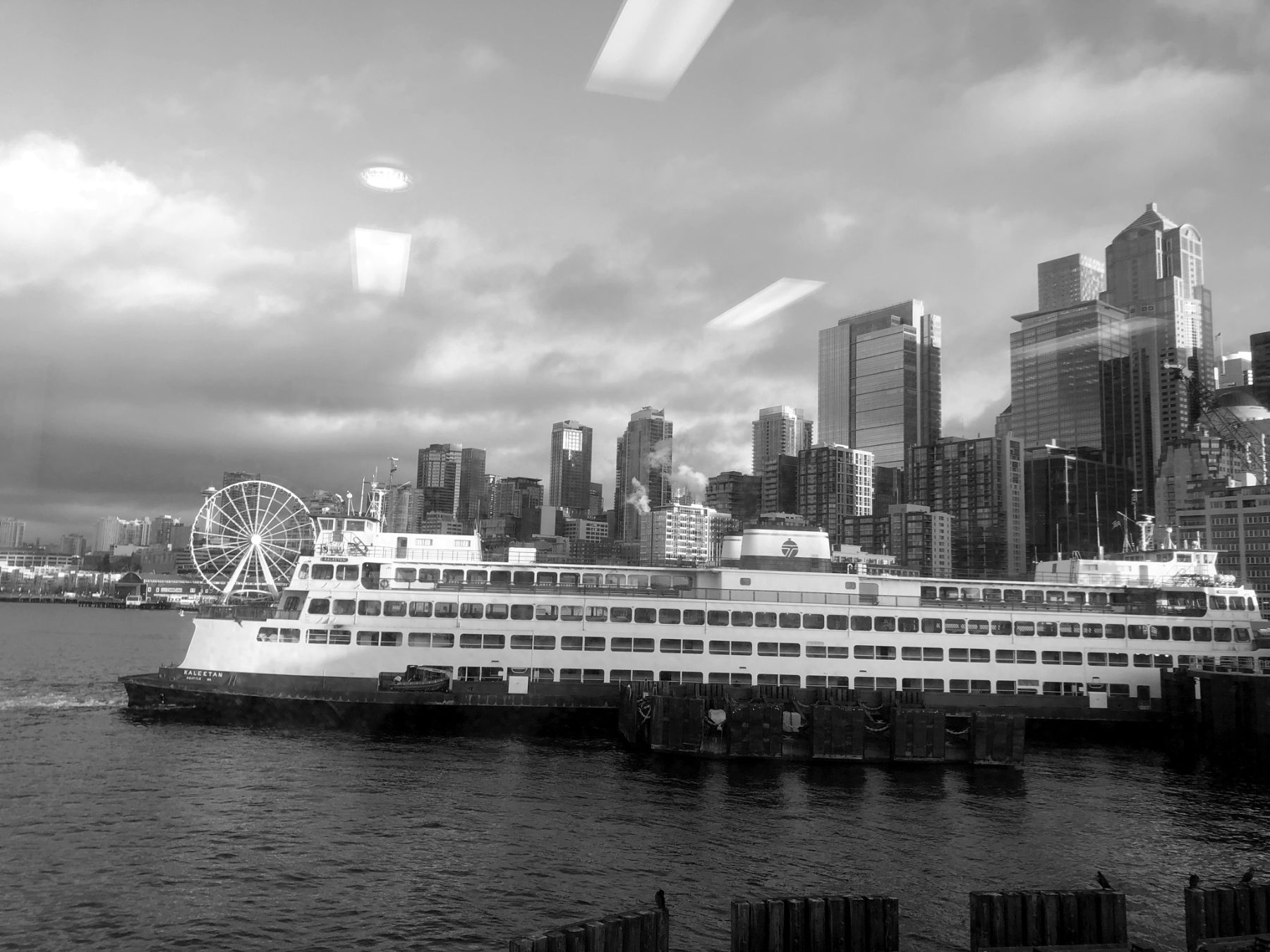 A ferry crossing toward the Seattle skyline under heavy cloud.