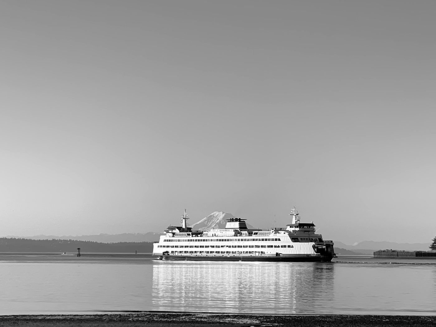 A Washington State ferry crossing open water with Mount Rainier behind it.