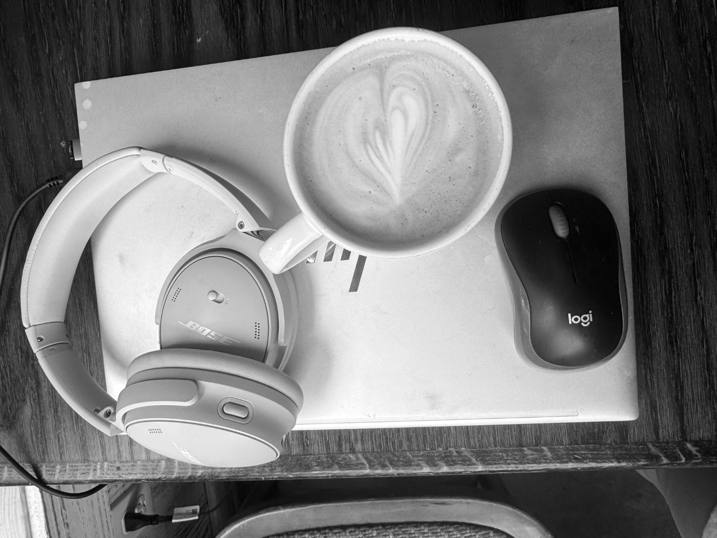 A laptop, headphones and a latte on a desk.