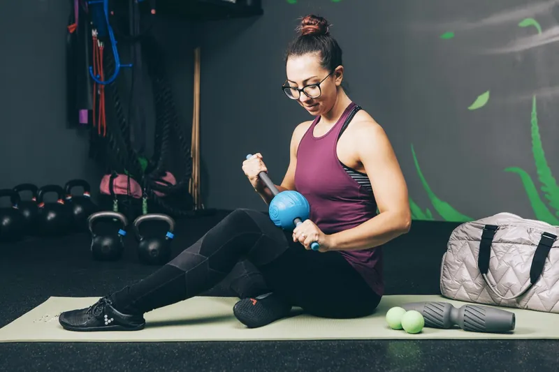 Woman releasing her leg with a RAD tool on a gym mat