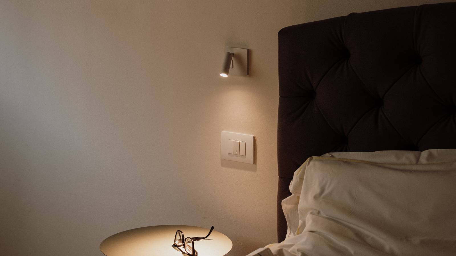 A hotel bedside lamp glowing in a quiet room