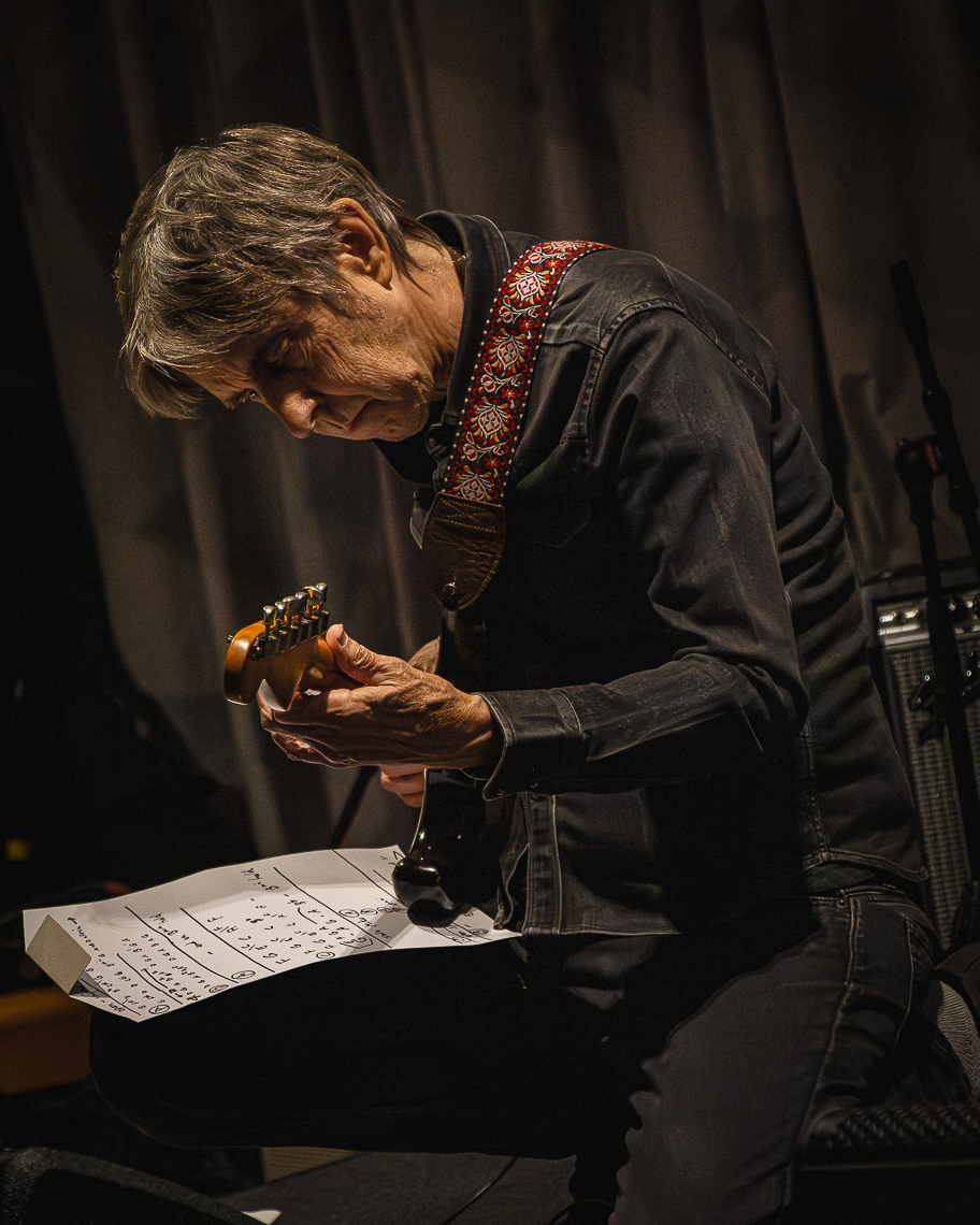 A guitarist leaning over his guitar with sheet music during a masterclass