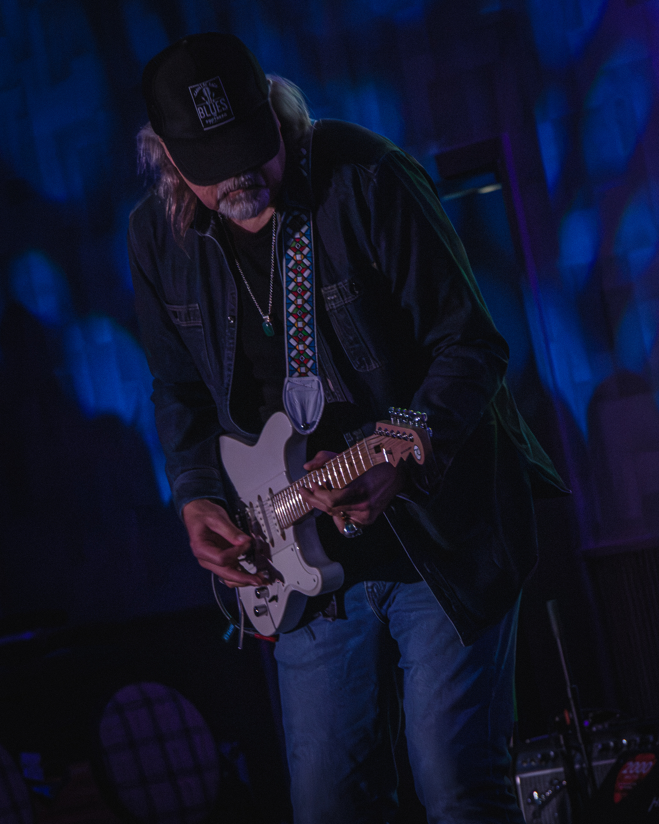 A guitarist on stage under blue light