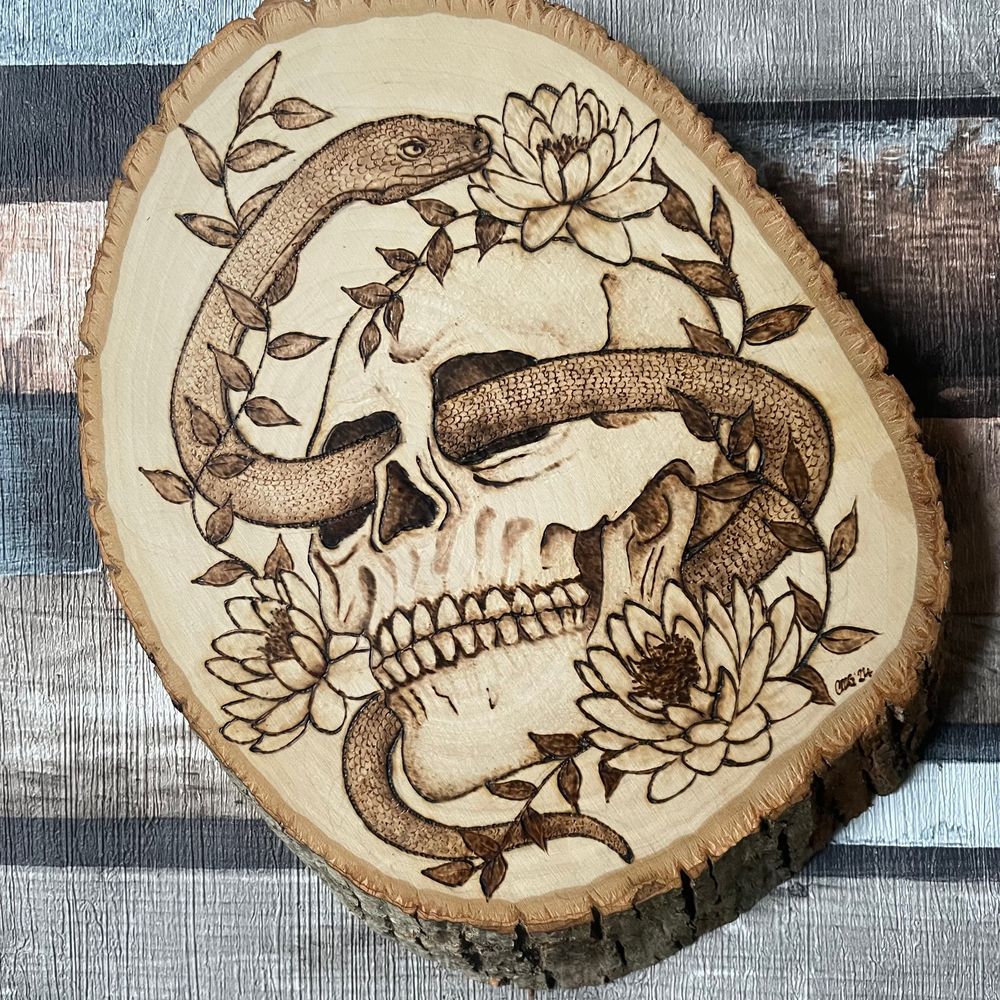 Burned skull and snake with water lilies, showing controlled shading and scale texture