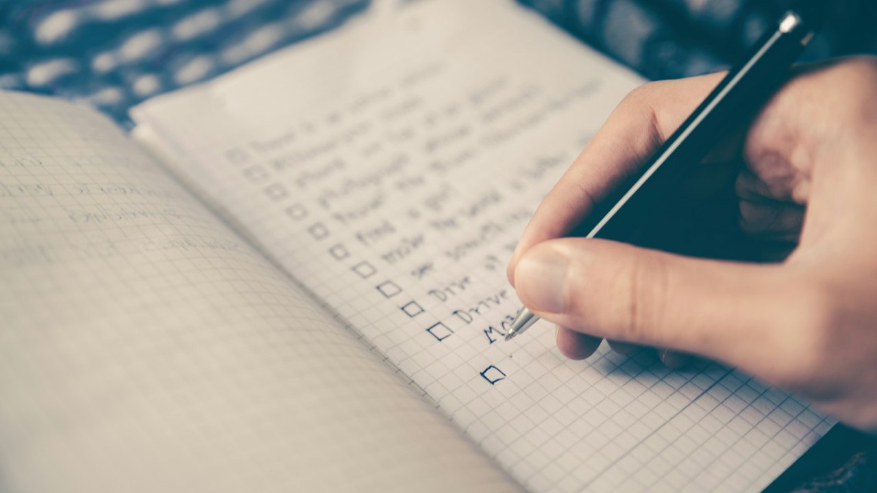 Hand writing an unchecked list in an open notebook