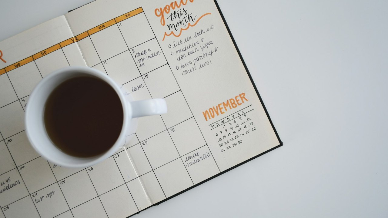 Open monthly planner with a cup of coffee resting on the page