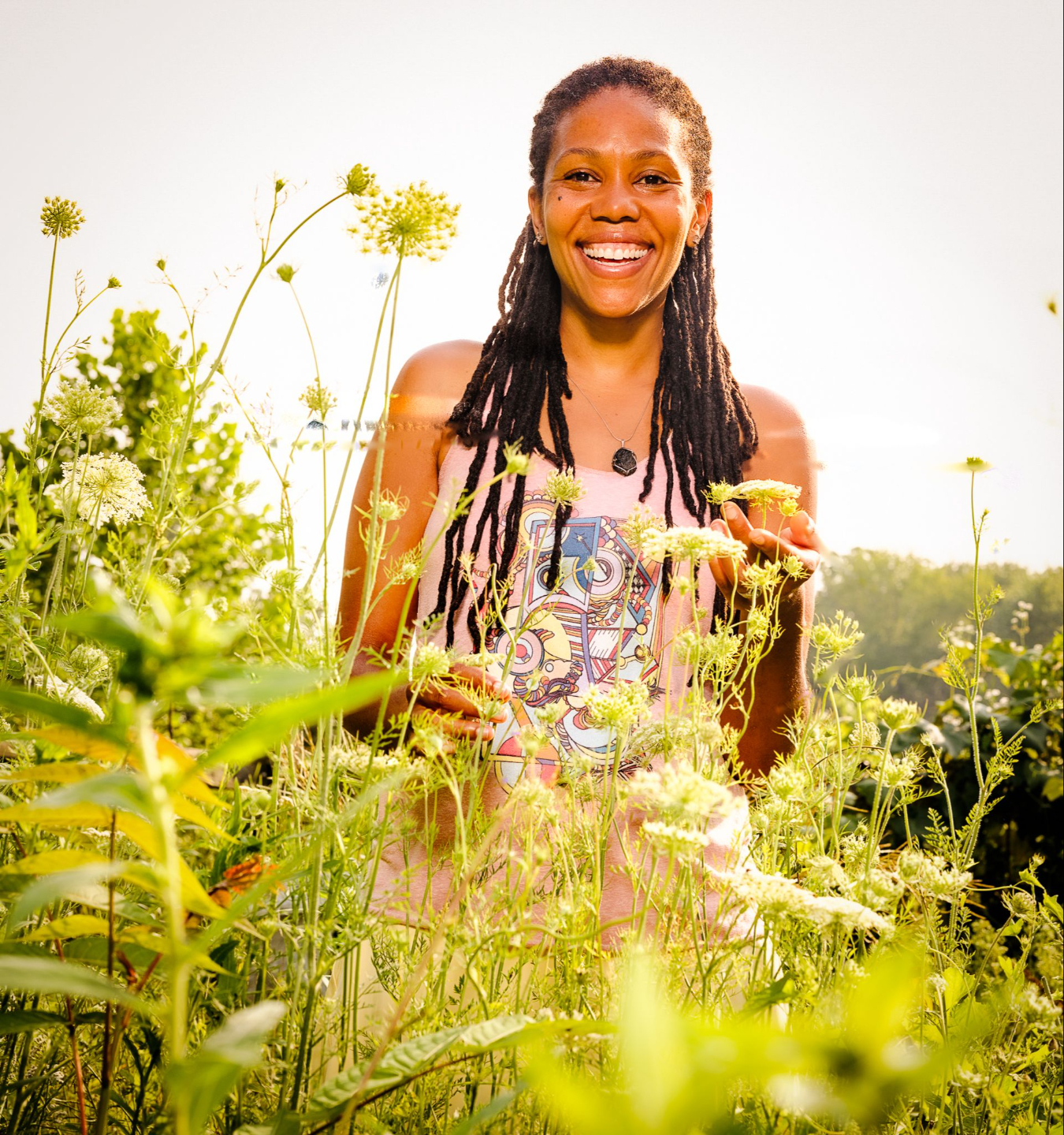 Selima smiling among plants in a field
