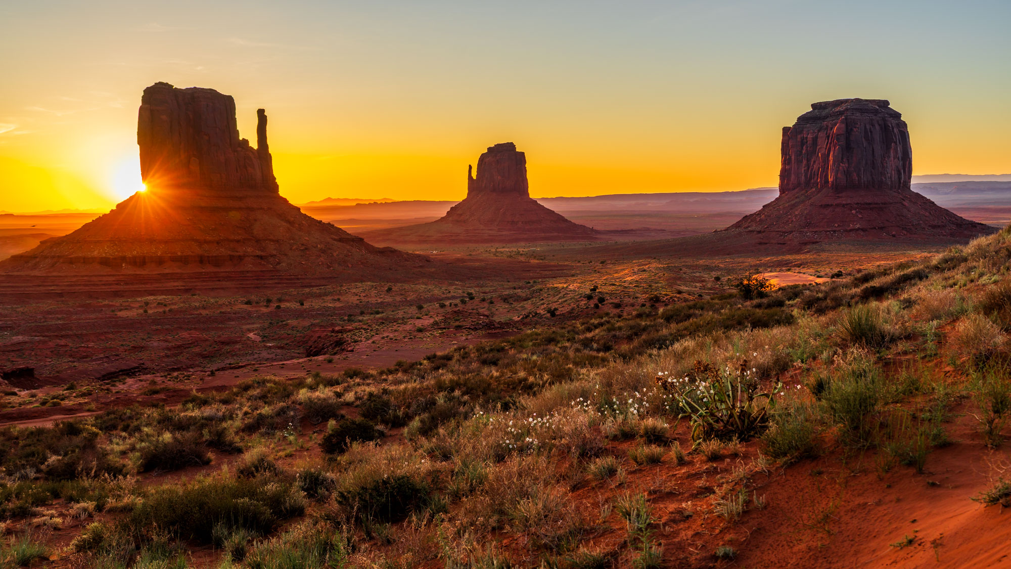 Sunrise over the Mittens and Merrick Butte in Monument Valley
