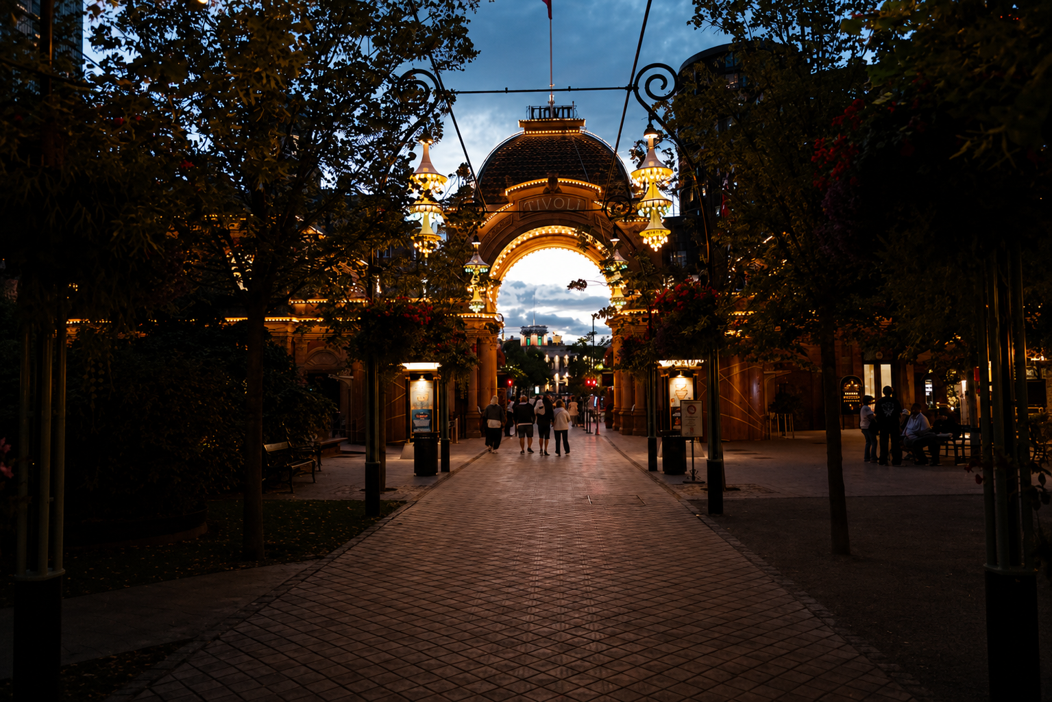 Tivoli Gardens' entrance at blue hour, full of visitors passing under the arch