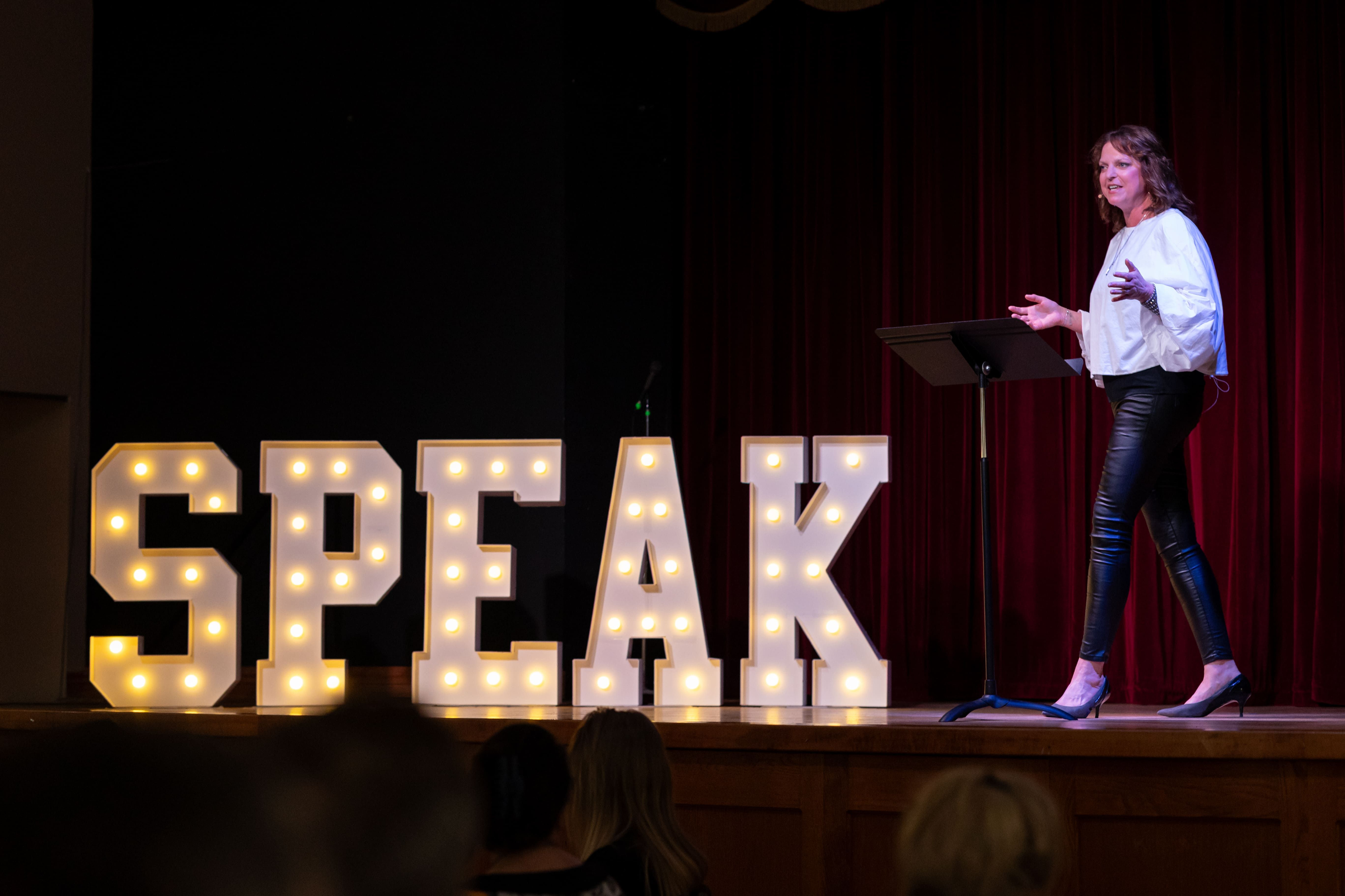 Jen McCallum on stage with SPEAK marquee sign