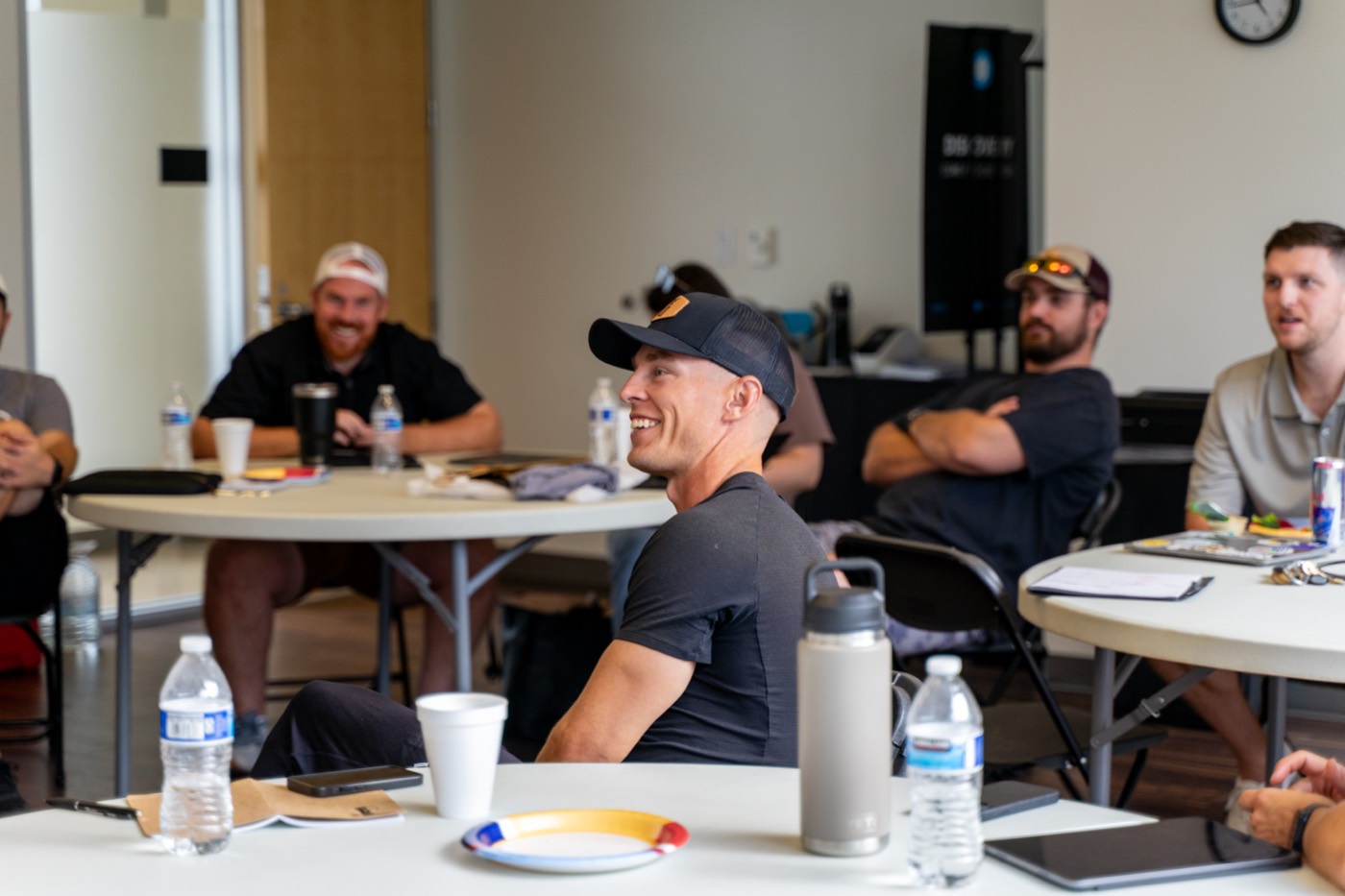 Leaders laughing around tables at a Leader Community