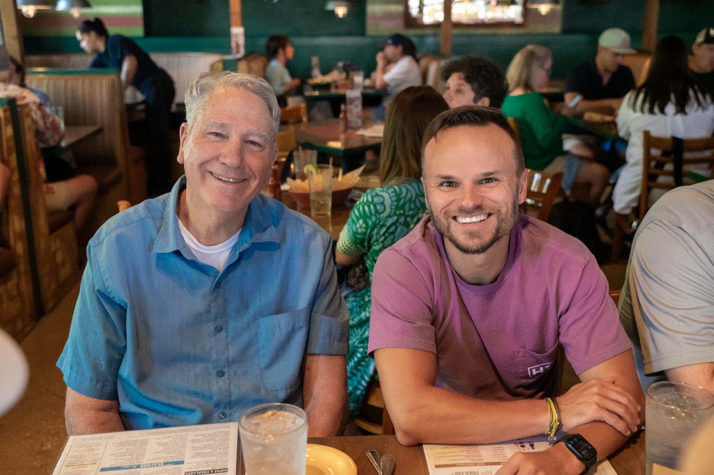An older and a younger ministry leader smiling side by side